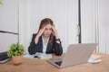 Asian businesswoman is tired and stressed while working focusing on laptop in modern office Royalty Free Stock Photo