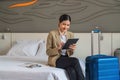 Businesswoman traveller sitting on bed using computer tablet in hotel room Royalty Free Stock Photo