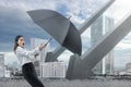 Asian businesswoman tries to hold back a falling arrow with a black umbrella