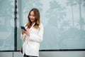 Asian businesswoman typing text on mobile phone standing outdoors street front building near office Royalty Free Stock Photo