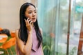 Asian businesswoman using phone by window in modern office