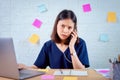 Asian businesswoman using smartphone with feeling strain from hard work for a long time in the desk office room. Royalty Free Stock Photo