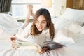 Asian businesswoman wear glasses and reading book on bed