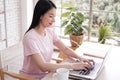 Asian businesswoman in white shirt is smiling and online working with laptop at home. She is blogger freelance in social media