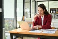 Asian businesswoman working at her desk, hand on chin, using laptop, thinking and planning project Royalty Free Stock Photo