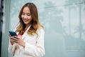 Asian businesswoman working with mobile phone standing against street front building near office Royalty Free Stock Photo