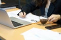 Asian businesswoman writing sales report with black pen On the desk with a notebook computer. And sales report paper. using as bac Royalty Free Stock Photo