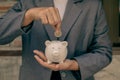 Asian businesswomen hold piggy banks and put coins in piggy banks to save money with coins to step into business, grow successful
