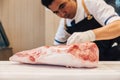 Asian butcher is cutting premium rare slices of Wagyu A5 beef with high-marbled texture on kitchen counter. Served for Yakiniku.