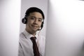 Asian call centre operator wearing headset with microphone sitting with computer in customer service department Royalty Free Stock Photo