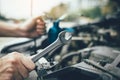 Asian car mechanic holds a wrench and a bottle of lure oil, ready to repair the car Royalty Free Stock Photo