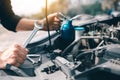 Asian car mechanic holds a wrench and a bottle of lure oil, ready to repair the car Royalty Free Stock Photo