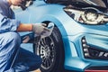 Asian car mechanic technician holding clipboard and checking to maintenance vehicle by customer claim order in auto repair shop