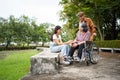 Asian careful caregiver or nurse taking care of the patient is hurting knee in wheelchair. Concept of happy retirement with care Royalty Free Stock Photo