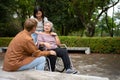 Asian careful caregiver or nurse taking care of the patient is hurting knee in wheelchair. Concept of happy retirement with care Royalty Free Stock Photo