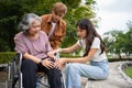 Asian careful caregiver or nurse taking care of the patient is hurting knee in wheelchair. Concept of happy retirement with care Royalty Free Stock Photo