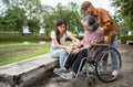 Asian careful caregiver or nurse taking care of the patient is hurting knee in wheelchair. Concept of happy retirement with care Royalty Free Stock Photo