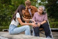 Asian careful caregiver or nurse taking care of the patient is hurting knee in wheelchair. Concept of happy retirement with care Royalty Free Stock Photo