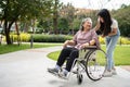 Asian careful caregiver or nurse taking care of the patient in a wheelchair. Concept of happy retirement with care from a Royalty Free Stock Photo