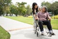 Asian careful caregiver or nurse taking care of the patient in a wheelchair. Concept of happy retirement with care from a Royalty Free Stock Photo