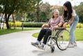Asian careful caregiver or nurse taking care of the patient in a wheelchair. Concept of happy retirement with care from a Royalty Free Stock Photo