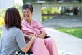 Asian careful caregiver or nurse taking care of the patient in a wheelchair. Concept of a happy retirement with care from a