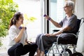 Asian caregiver is doing physical therapy for the old elderly,disabled senior woman in a wheelchair,exercise use dumbbells to help