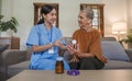 Asian caregiver nurse give consult to Caucasian senior woman 60s patient. Attractive care pharmacist hold medicine pills Royalty Free Stock Photo