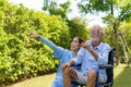 Asian caregiver nurse with senior man sitting on wheelchair in garden and looking nature around home in morning Royalty Free Stock Photo