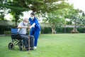 Asian Caregiver wear mask, take care senior disabled man on wheelchair. Young beautiful woman carer nurse at nursing home support Royalty Free Stock Photo