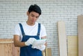 Asian carpenter inspect the list of items that must be done as scheduled, deliver the work with a happy face. Wood planks of