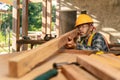Asian carpenter visually examines the accuracy of the wood at construction site