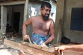 Asian carpenter working with wooden plane at a furniture workshop