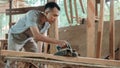 Asian carpenters work using electric wood dowels when smoothing wood surfaces