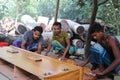 Asian carpentry workers polishing a painted bed part at a furniture workshop