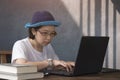 Asian casual woman using laptop computer on wooden desk while work from home in home office room Royalty Free Stock Photo