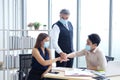 Asian and Caucasian businesspeople teamwork wearing mask preventing for covid 19 virus and joining hands together for successful