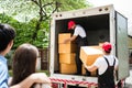 Asian and Caucasian workers in uniform unloading cardboard boxes from the truck. Delivery men unloading boxes and check. Royalty Free Stock Photo