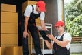 Asian and Caucasian workers in uniform unloading cardboard boxes from the truck. Delivery men unloading boxes and check. Royalty Free Stock Photo