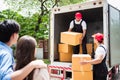 Asian and Caucasian workers in uniform unloading cardboard boxes from the truck. Delivery men unloading boxes and check. Royalty Free Stock Photo