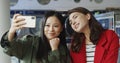 Asian and Caucasian young beautiful girls smiling and posing to smartphone camera while taking selfie photo in laundry Royalty Free Stock Photo