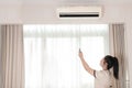 Young Asian chambermaid working in a hotel room She is holding a remote control and appears to be opening the air conditioning Royalty Free Stock Photo