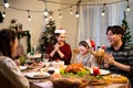 Asian cheerful family applauding hand and singing a song on the Christmas dinner table with turkey roasted, strawberry cake, snack