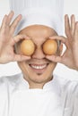 Asian chef holding eggs in front of eyes. Conceptual image Royalty Free Stock Photo