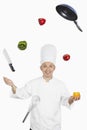 Asian chef juggling vegetables and kitchen utensil. Conceptual image