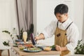 Asian chef making sushi rolls on the kitchen. Adds sauce to sushi. Food delivery concept Royalty Free Stock Photo