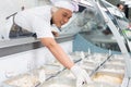 Asian chef placing food into a glass counter