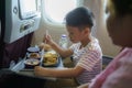 Asian Child in airplane window seat. Kids flight meal. Children fly. Special inflight menu, food and drink for baby and kid. Boy Royalty Free Stock Photo