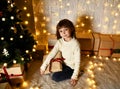 Asian child baby girl kid sitting under decorated gold Christmas tree with gold patchwork gift presents Royalty Free Stock Photo