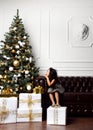 Asian child baby girl kid sitting under decorated gold Christmas tree with gold patchwork gift presents Royalty Free Stock Photo